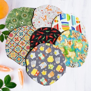 May include: Set of 10 colorful fabric round placemats with various designs. The placemats feature a variety of patterns, including floral, geometric, and animal prints. The placemats are perfect for adding a touch of style to any dining table.