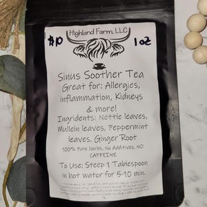 Puede incluir: Una bolsa negra de "Sinus Soother Tea" de Highland Farm, LLC. La etiqueta enumera ingredientes como hojas de ortiga, hojas de menta y raíz de jengibre. El texto también indica que el té es bueno para las alergias y la inflamación. La bolsa es de 28 g.