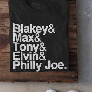 May include: Black t-shirt with white text that reads "Blakey & Max & Tony & Elvin & Philly Joe."