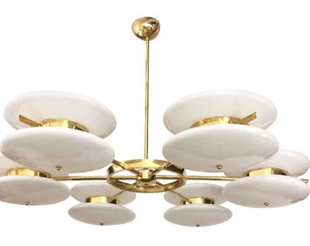 May include: A brass and white glass chandelier with eight circular lights. The chandelier has a central brass rod with a circular brass frame and eight white glass shades.