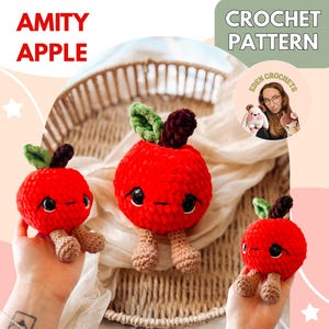 Op de afbeelding: Drie rode gehaakte appel speelgoed met zwarte ogen, groene bladeren en bruine benen worden getoond. De tekst "AMITY APPLE" en "CROCHET PATTERN" zijn zichtbaar. De appels zijn handgemaakt en hebben een grillig ontwerp.