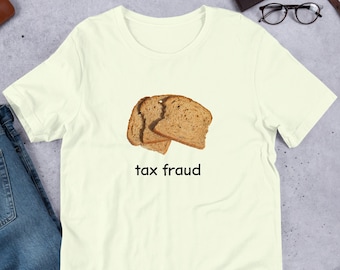 May include: A light yellow t-shirt featuring a graphic of two slices of bread and the text "tax fraud".