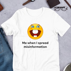 May include: White t-shirt with a yellow smiley face and the text "Me when I spread misinformation".