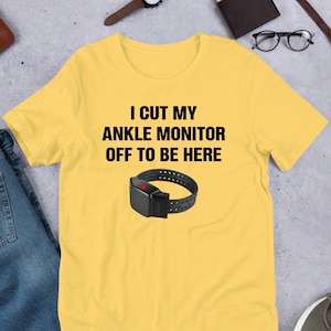 May include: Yellow t-shirt with the text "I cut my ankle monitor off to be here" and a black ankle monitor graphic.