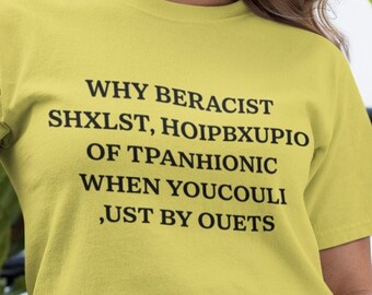 May include: A pale yellow t-shirt with black text. The text reads: "WHY BERACIST SHXLST, HOIPBXUPIO OF TPANHIONIC WHEN YOUCOULI, UST BY OUETS". The shirt is paired with blue denim jeans.