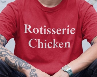 Puede incluir: Un hombre con una camiseta roja con el texto "Rotisserie Chicken" en letras blancas. Lleva una gorra de béisbol azul y pantalones vaqueros negros.