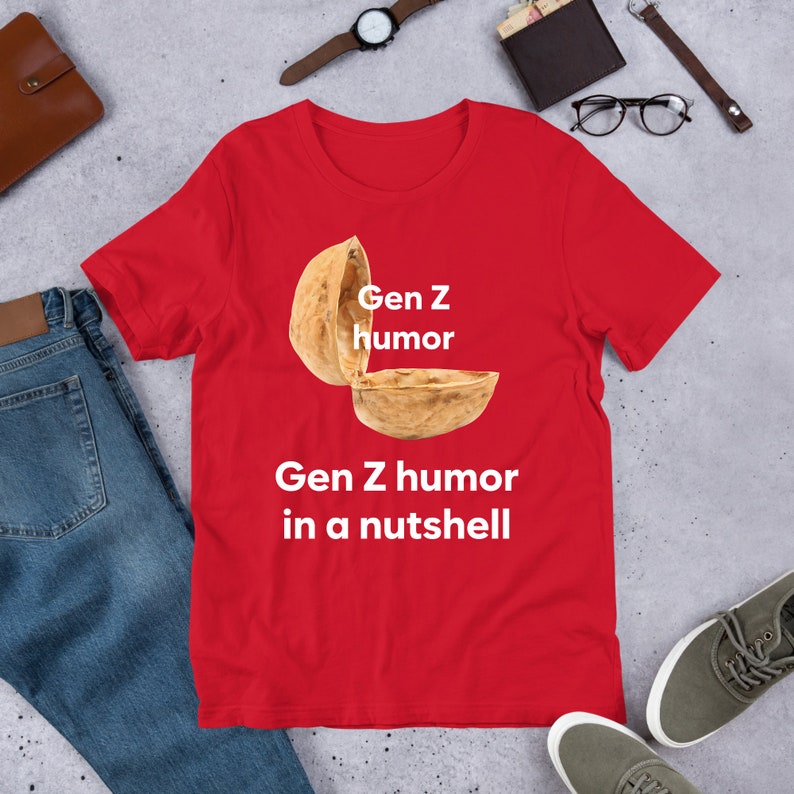 May include: Red t-shirt with a white graphic of a walnut shell with the text "Gen Z humor" and "Gen Z humor in a nutshell" printed below.