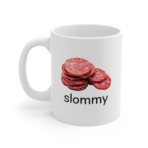 May include: White ceramic mug with a picture of sliced salami and the word "slommy" printed in black.