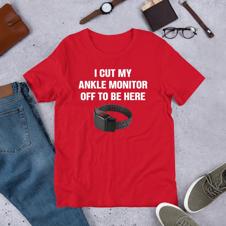 May include: Red t-shirt with white text that reads "I cut my ankle monitor off to be here". A black ankle monitor is pictured below the text.