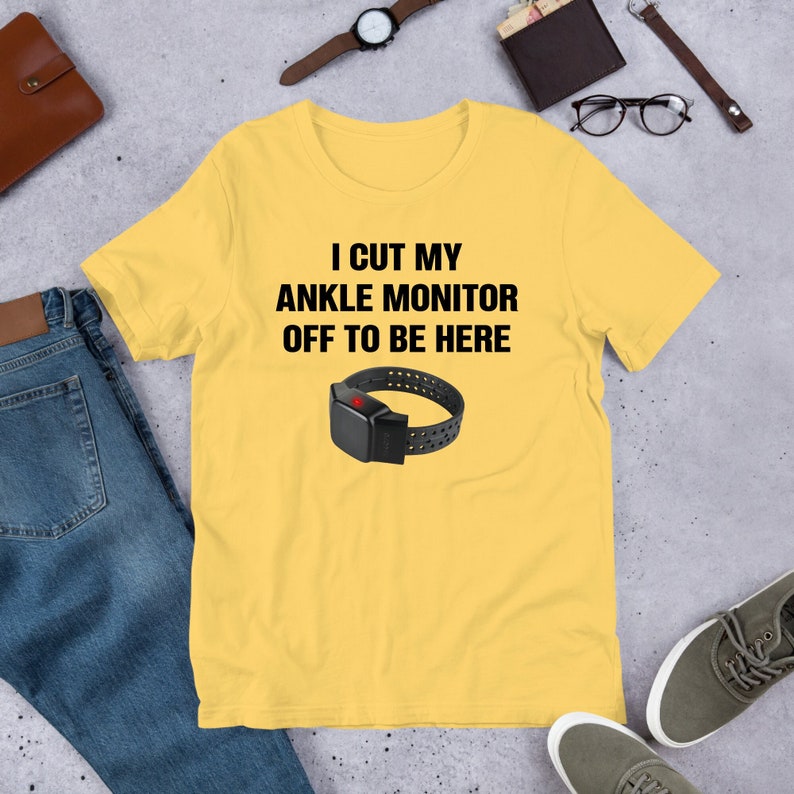 May include: Yellow t-shirt with the text "I cut my ankle monitor off to be here" and a black ankle monitor graphic.
