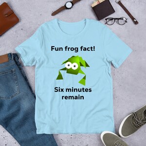 May include: Light blue t-shirt with a green cartoon frog and the text "Fun frog fact! Six minutes remain".
