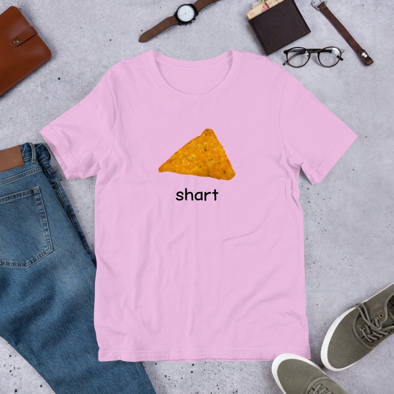 May include: A pink t-shirt with a picture of a nacho chip and the word "shart" printed on it.
