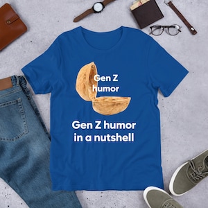 May include: A royal blue t-shirt with a white graphic of a walnut shell with the text "Gen Z humor" and "Gen Z humor in a nutshell" printed on the front.