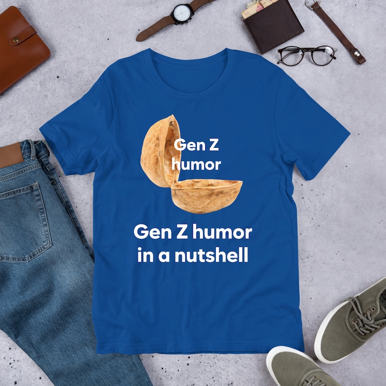May include: A royal blue t-shirt with a white graphic of a walnut shell with the text "Gen Z humor" and "Gen Z humor in a nutshell" printed on the front.