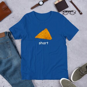May include: A royal blue t-shirt with a picture of a nacho chip and the word "shart" printed on it.