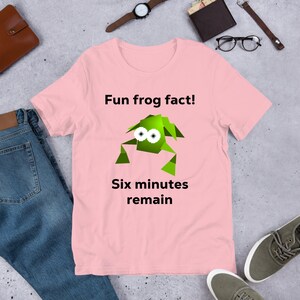 May include: Pink t-shirt with a green cartoon frog and the text "Fun frog fact! Six minutes remain."