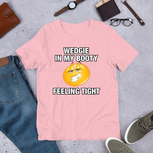 May include: Pink t-shirt with a yellow smiley face and the text "WEDGIE IN MY BOOTY FEELING TIGHT"