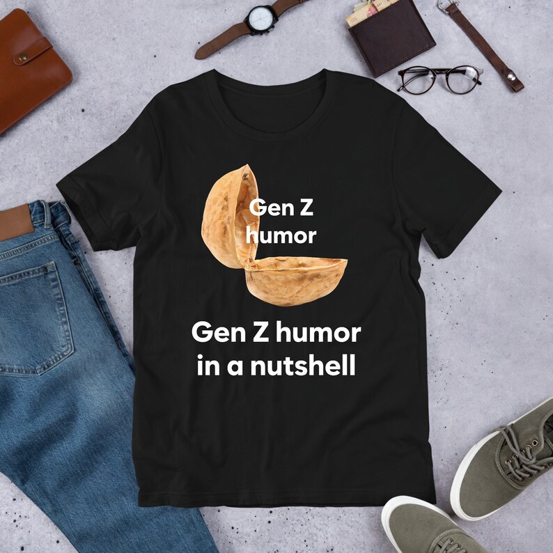 May include: Black t-shirt with a white graphic of a walnut shell with the text "Gen Z humor" and "Gen Z humor in a nutshell" below it.