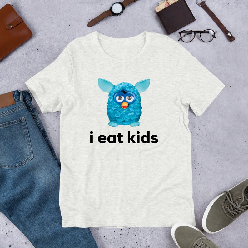 May include: A white t-shirt with a blue fuzzy creature with big eyes and the text "i eat kids" printed on it.