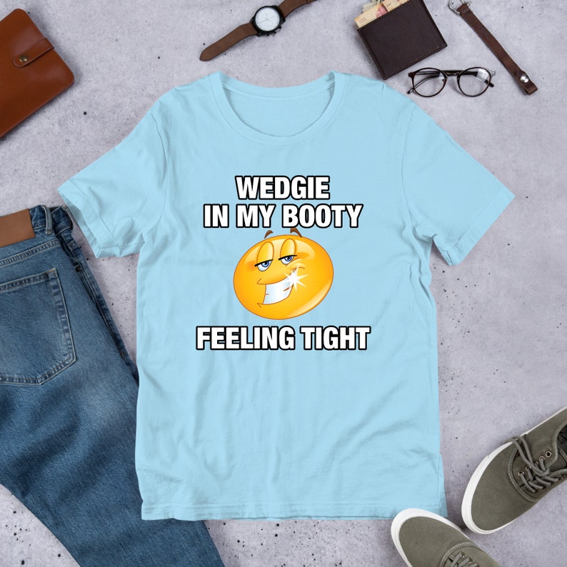 May include: Light blue t-shirt with a yellow smiley face and the text "WEDGIE IN MY BOOTY FEELING TIGHT"