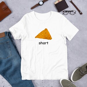 May include: White t-shirt with a picture of a tortilla chip and the word "shart" printed on it.