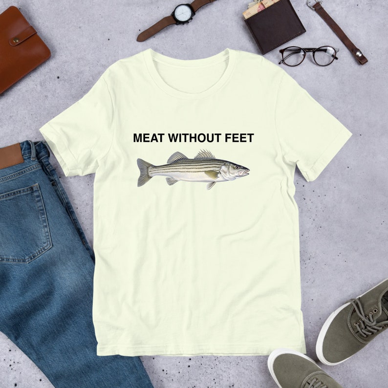 May include: A light yellow t-shirt with a black and white striped fish illustration and the text "MEAT WITHOUT FEET" printed on the front.