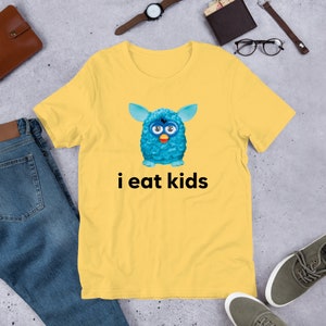 May include: A yellow t-shirt with a blue fuzzy creature and the text "i eat kids" printed on it.