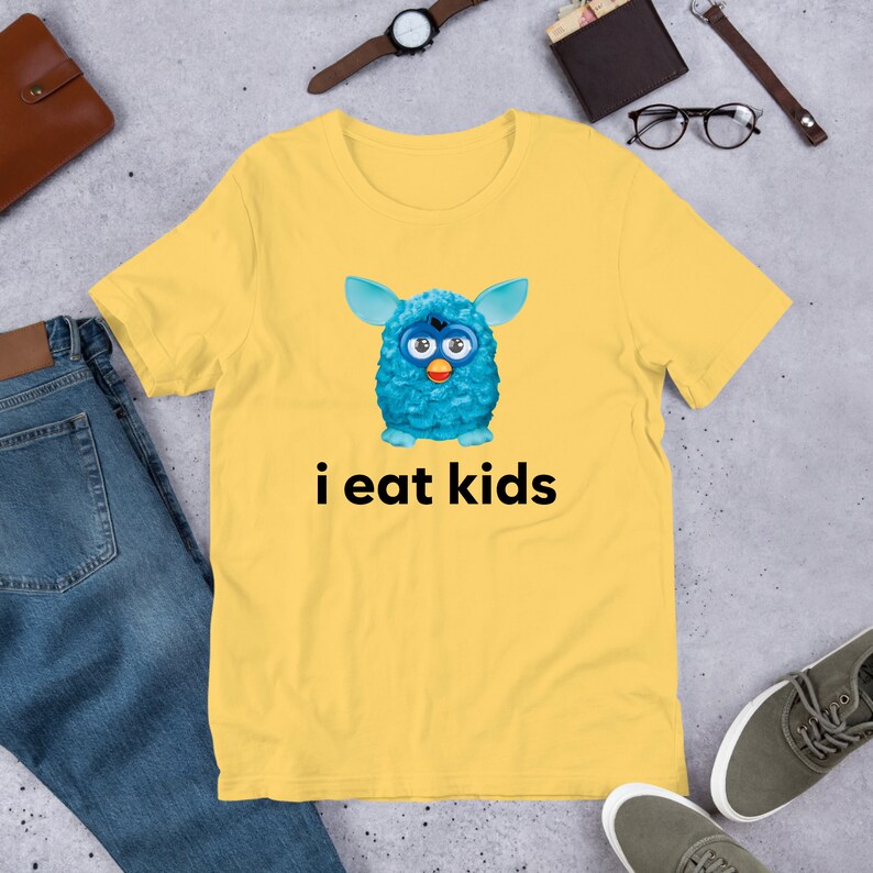May include: A yellow t-shirt with a blue fuzzy creature and the text "i eat kids" printed on it.