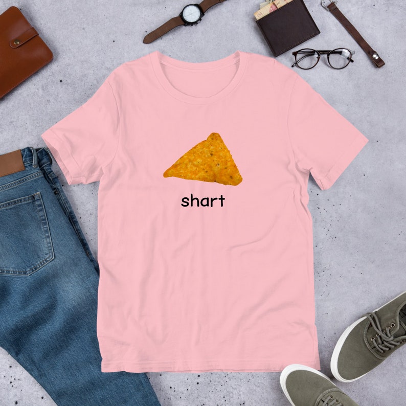 May include: A pink t-shirt with a graphic of a tortilla chip and the word "shart" printed on it.