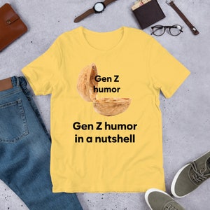 May include: Yellow t-shirt with a graphic of a walnut with the text "Gen Z humor" above it and "Gen Z humor in a nutshell" below it.