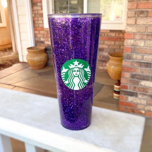 May include: Purple glitter tumbler with a green Starbucks logo.