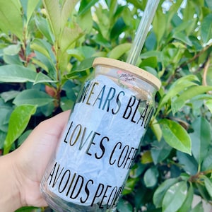 May include: A clear glass jar with a bamboo lid and a glass straw. The jar has black lettering that reads "Wears Black, Loves Coffee, Avoids People".