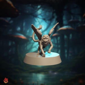 Puede incluir: Figura gris de un mono alado con la boca abierta y los dientes descubiertos, posada sobre una base redonda. El mono tiene grandes alas y está en posición agachada. El fondo es una escena de bosque borrosa.