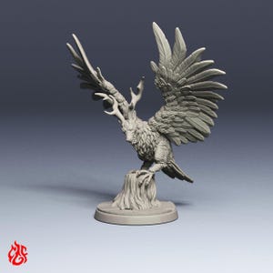 May include: A gray unpainted miniature figurine of a mythical creature with the body of a bird, large feathered wings spread wide, and a head featuring deer-like antlers. The creature is perched on a textured tree stump base.