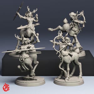 Op de afbeelding: Vier grijze hars miniatuurfiguurtjes die centaur-achtige wezens uitbeelden met hertachtige kenmerken, waaronder geweien en hoeven. Twee figuren houden speren vast, terwijl de andere twee poseren met pijl en boog, allemaal op ronde voetstukken.