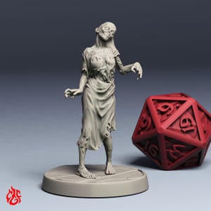 Könnte beinhalten: Eine graue, 3D-gedruckte Zombie-Miniatur, die auf einer kreisförmigen Basis steht. Die Figur trägt zerfetzte Kleidung und hat ein skelettartiges Gesicht. Ein großer roter zwanzigseitiger Würfel befindet sich neben der Figur, für Tabletop-Spiele.