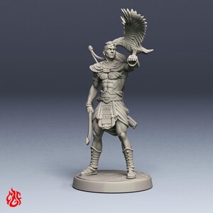 Op de afbeelding: Een grijs onbeschilderd miniatuurfiguur van een krijger op een ronde voet. Het figuur heeft een valk op de uitgestrekte arm, draagt een versierd borstpantser, een lendendoek en beenwindsels, en houdt een gebogen zwaard in de andere hand.