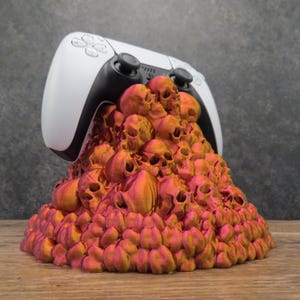 Op de afbeelding: Een witte PlayStation 5-controller ligt op een stapel rood-oranje 3D-geprinte schedels.
