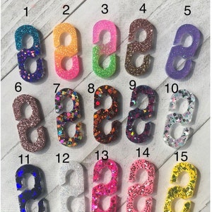 May include: Fifteen different colored glitter resin  'S' shaped hooks. The hooks are numbered 1 through 15. The text 'Buy 2 Get 1 FREE!!' is at the top of the image.