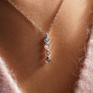 May include: A silver chain necklace with a pendant featuring four square-shaped gemstones in shades of blue, white, brown, and purple.