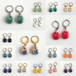 May include: Assortment of 20 pairs of earrings with various colors and patterns. Each pair features a round ceramic charm with a unique design. The earrings are made with silver and gold hoops.
