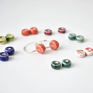 Kleurrijke oorringen met verwisselbare keramische schijfjes. Schattige handgemaakte geometrische oorbellen van klei en zilver.