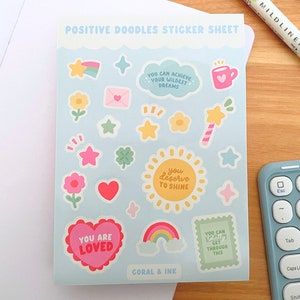 May include: A sticker sheet with a light blue background featuring positive affirmations and cute illustrations. The stickers include phrases like "You Can Achieve Your Wildest Dreams", "You Deserve To Shine", "You Are Loved", and "You Can Get Through This". The sheet also includes illustrations of stars, flowers, hearts, rainbows, and a cup of coffee.