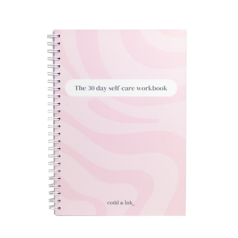 Może przedstawiać: Zeszyt do pracy nad samoopieką w kolorze r&oacute;żowym i białym z wzorem wirującym, z tytułem "The 30 day self-care workbook" i tekstem "coral & ink." na dole.