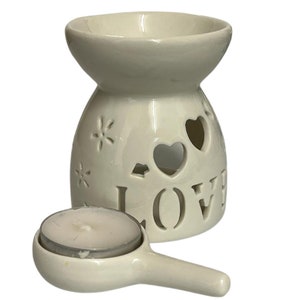 May include: White ceramic oil burner with a cutout design of hearts and the word "LOVE". It includes a small white ceramic dish with a tea light candle.