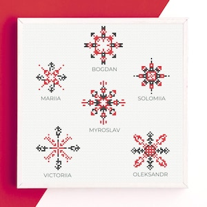 May include: A framed, white cross-stitch artwork featuring six geometric designs in red, black, and white. Each design is unique and accompanied by a name: Bogdan, Mariia, Solomiia, Myroslav, Victoriia, and Oleksandr.