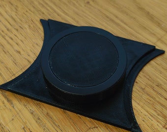 Puede incluir: Un objeto negro impreso en 3D con una parte superior circular y una base redondeada. El objeto está diseñado para sostener un objeto pequeño, como un anillo o una moneda.