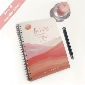May include: A pink and orange spiral bound journal with the words "Be still and know that I am God" and "Psalm 46:10" printed on the cover. The journal also has the words "Faith Shared" printed on the bottom of the cover.