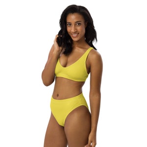 Op de afbeelding: Een gele bikini top en bijpassende hoge taille bikini broek. De bikini top heeft een ronde hals en de bikini broek heeft een hoge beenuitsnijding.