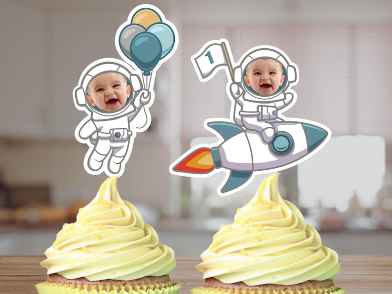 May include: Two cupcake toppers featuring an astronaut with a rocket and an astronaut holding balloons. The astronaut's faces are blank and can be personalized with photos. The toppers are perfect for a first birthday party.